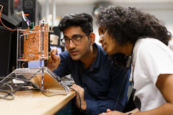 Two IU students working on a computer motherboard.