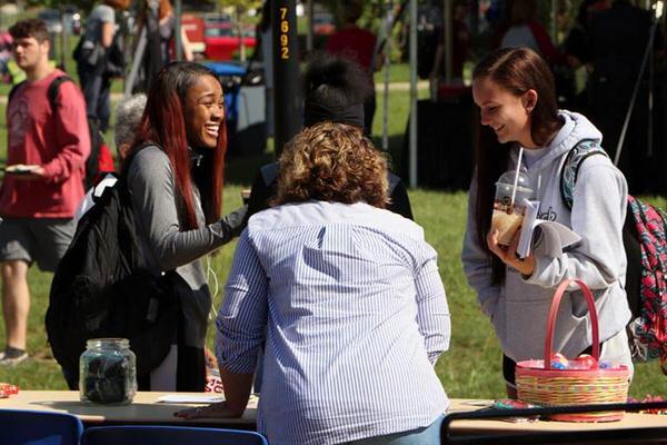 Two female students talking at an outdoor student club fair on the IU East campus.