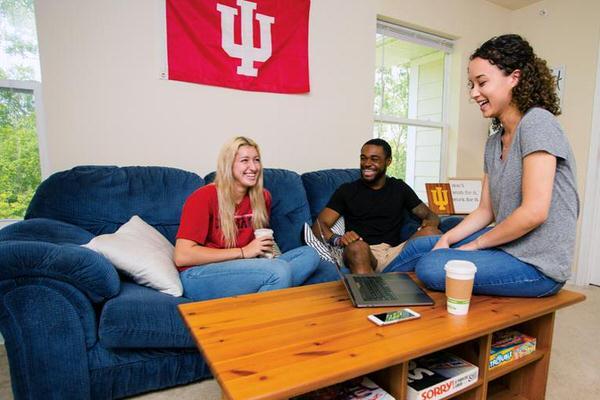 Three students sitting on couch in apartment.