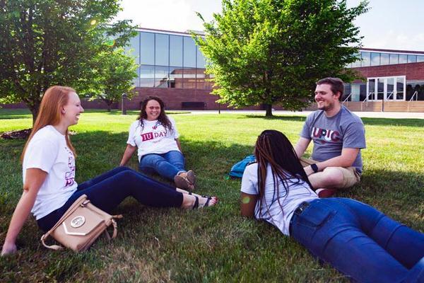 Four students sitting outside in the grass on IUPUC campus.
